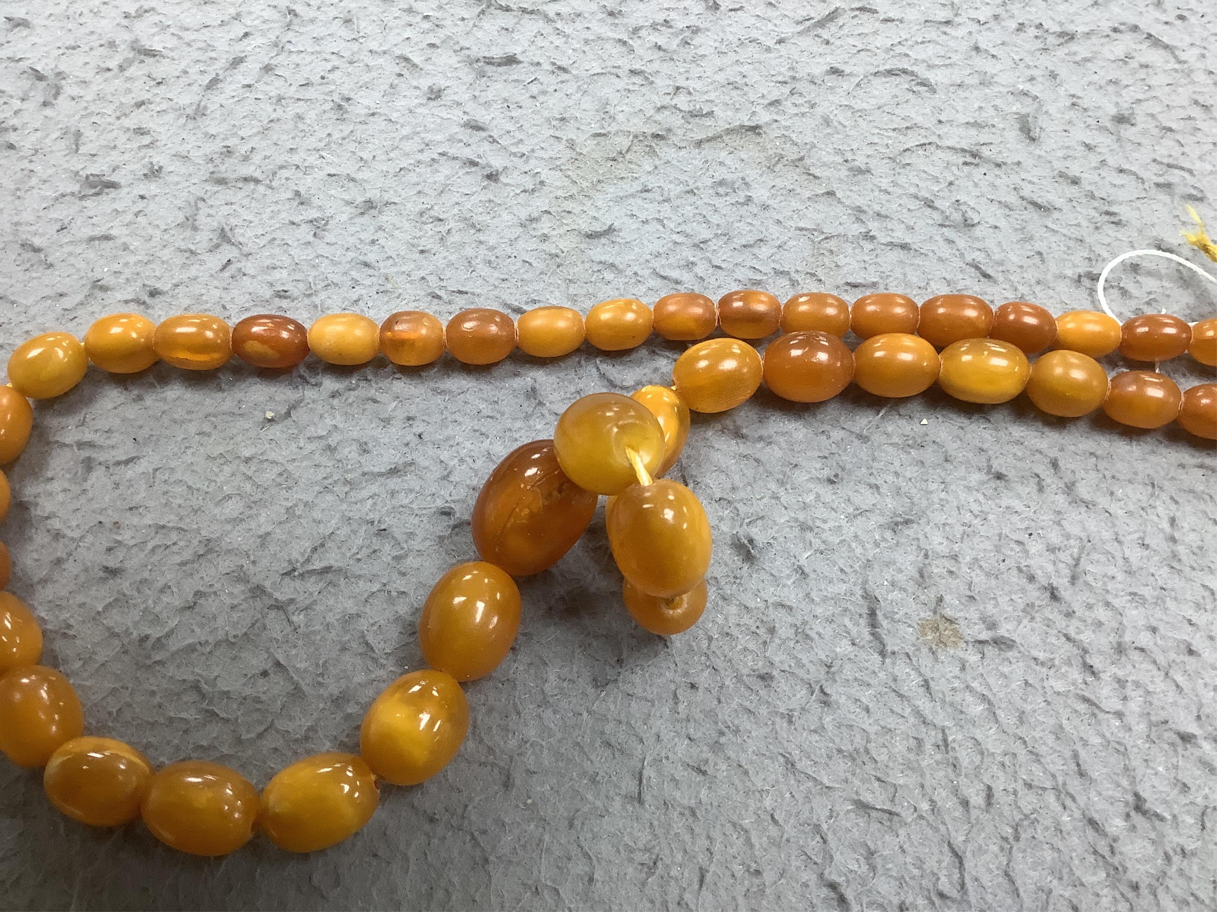 A single strand graduated oval amber bead necklace (a.f.), 90cm, gross weight 72 grams and three odd beads and an earring. Condition - poor